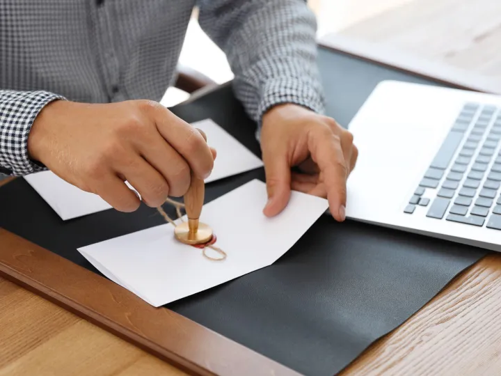 Hands pressing a wax seal onto a document at a desk