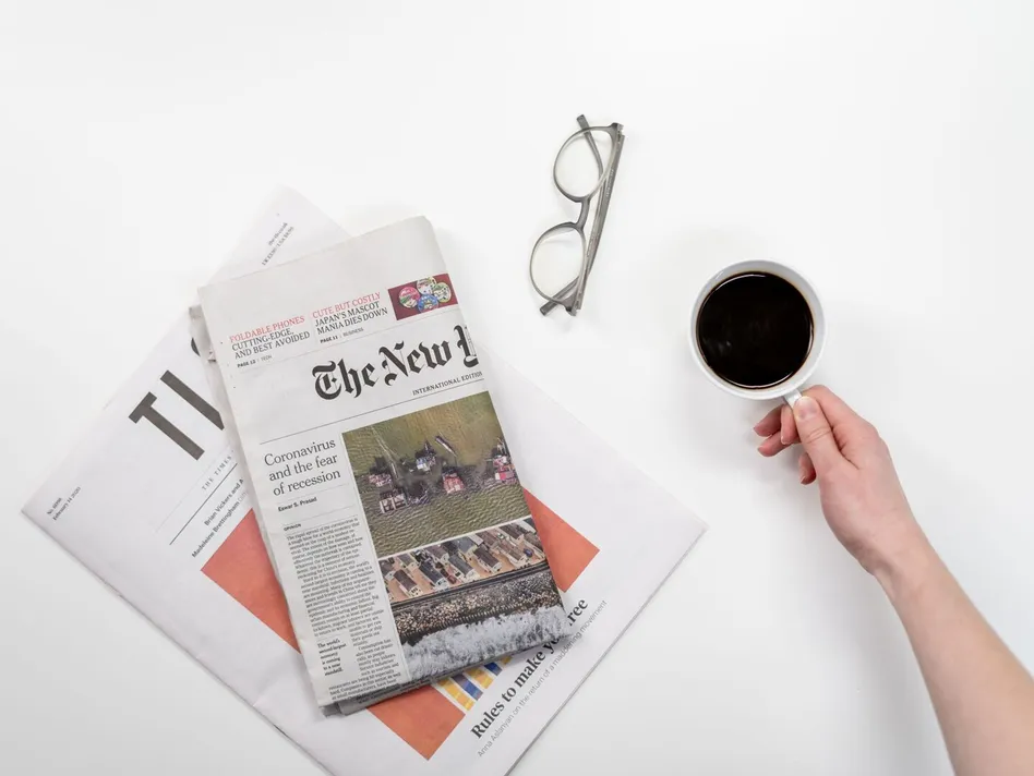 Top view of a coffee cup, newspapers, and