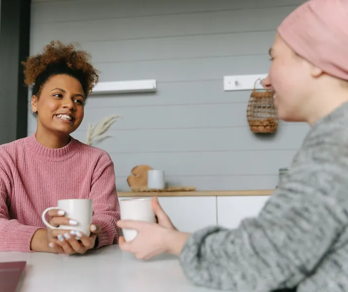 Two women share a joyful coffee moment at home