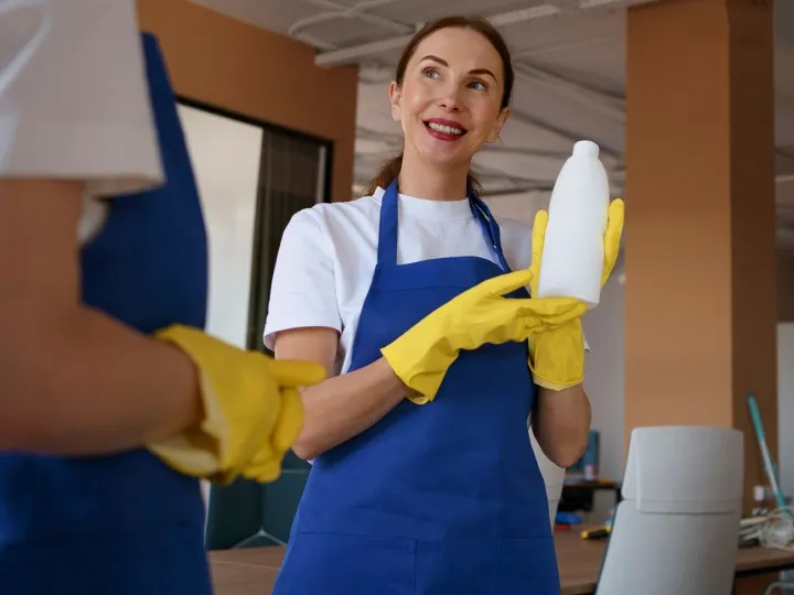 Smiling cleaner holding cleaning products