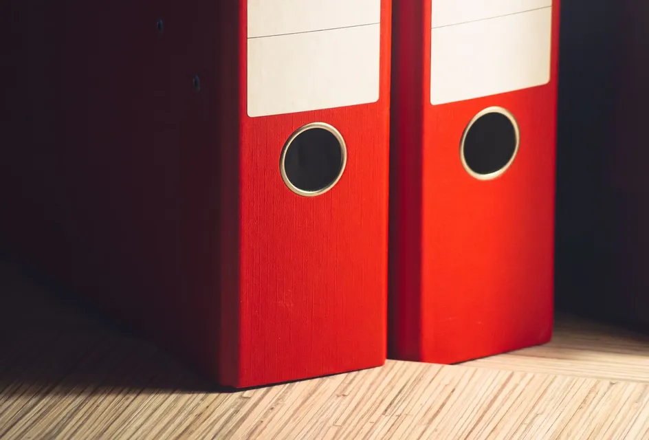 Two lever arch files on a wooden desk in an office