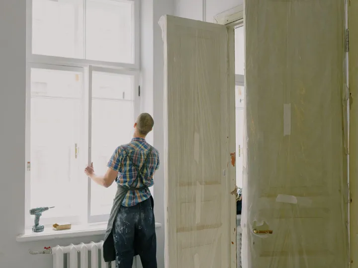 Handyman in an apron fitting a window during a renovation