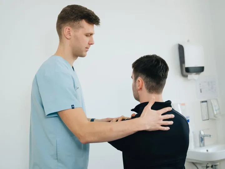 A physiotherapist assessing a patient’s shoulder in a clinic