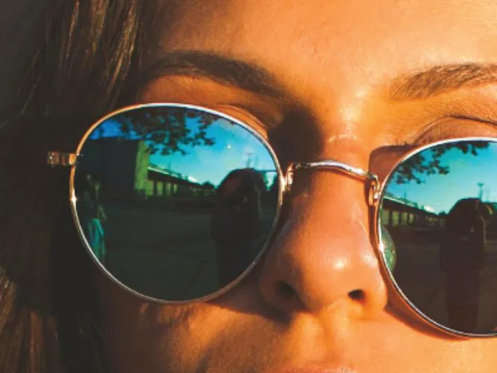Woman with gold-rimmed reflective sunglasses