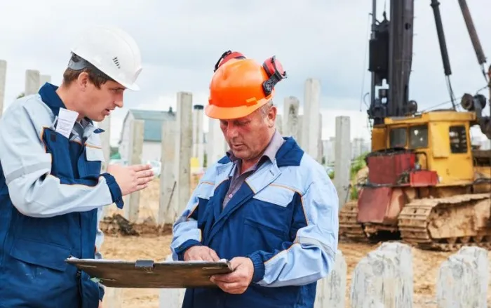 Construction workers in front of pile driver machine