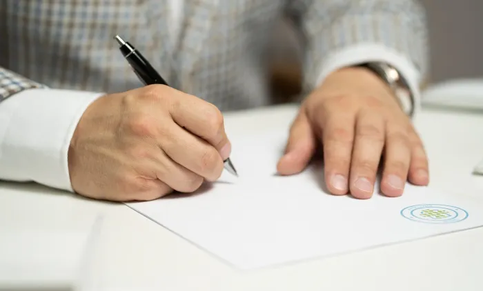 A hand signing a document with a pen