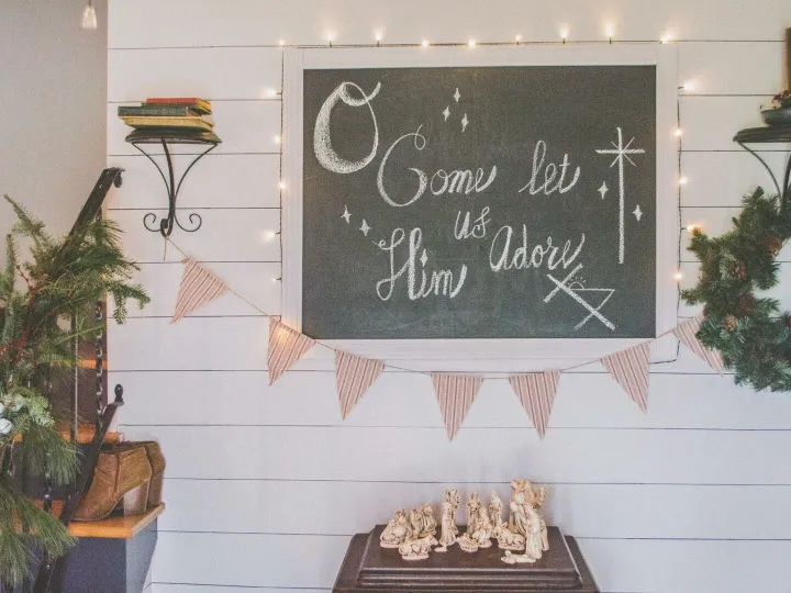 Festive Christmas setup featuring a chalkboard with holiday message, wreath, and nativity scene.
