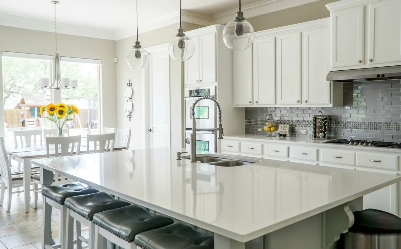 Spacious modern kitchen with white cabinets and island in natural light.