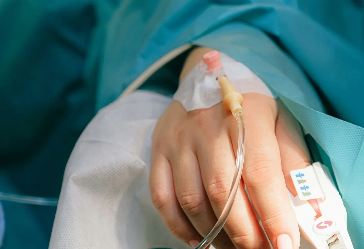 Close-up of a patient's hand with intravenous therapy and pulse oximeter, symbolizing healthcare and treatment.