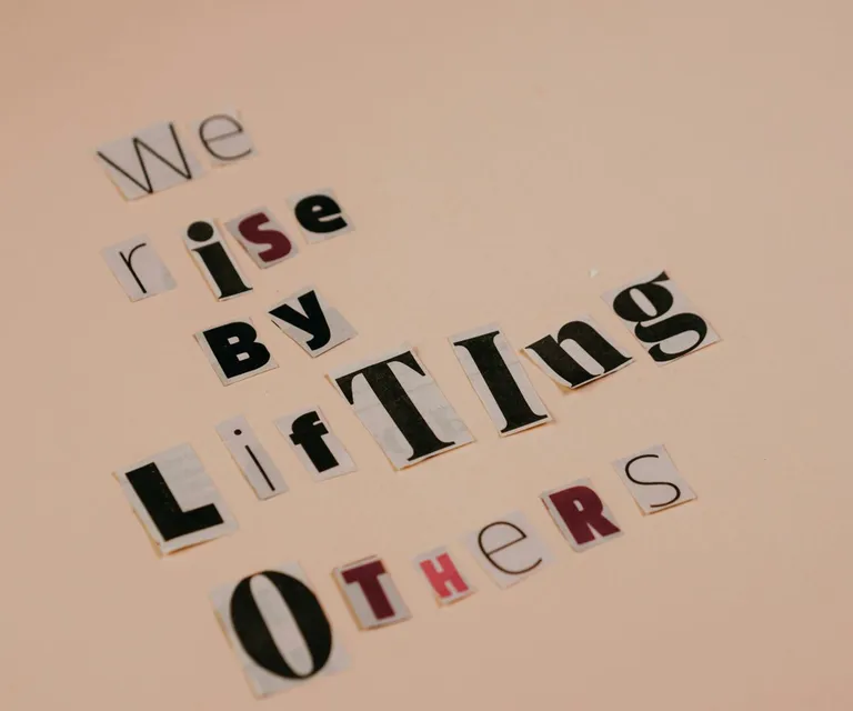 Cutout letters forming an inspirational quote on a beige background, encouraging positivity.
