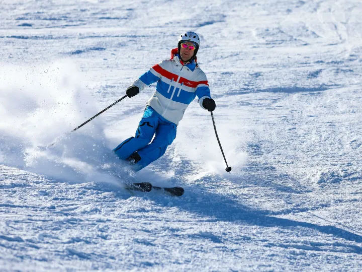Man skiing down snowy slope in Vorarlberg, Austria, on a sunny winter day.