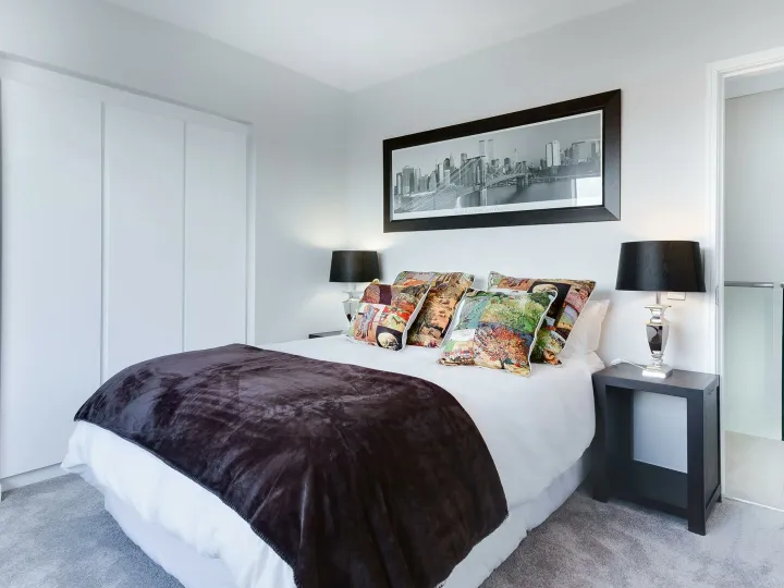 Stylish and contemporary bedroom featuring a cityscape artwork, colorful pillows, and modern decor.