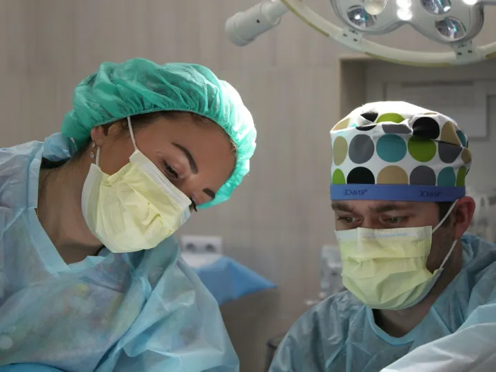 Surgeons wearing masks and scrubs conduct an operation in a hospital setting.