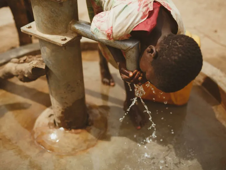 A girl bends to drink clean water from a well in Kitgum, Northern Uganda.