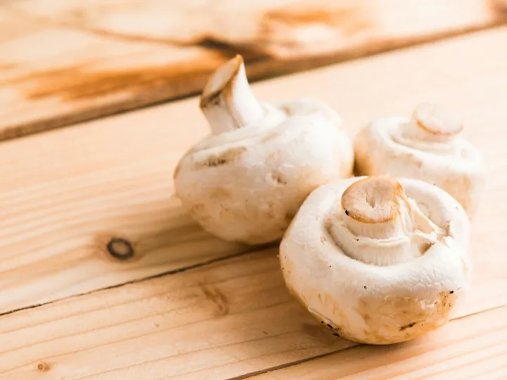 Fresh white mushrooms on a wooden table