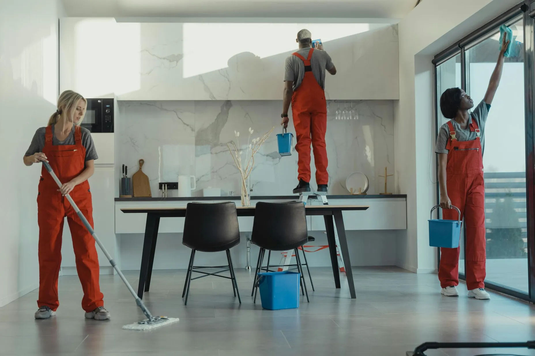 Group of cleaners in red uniforms mopping and