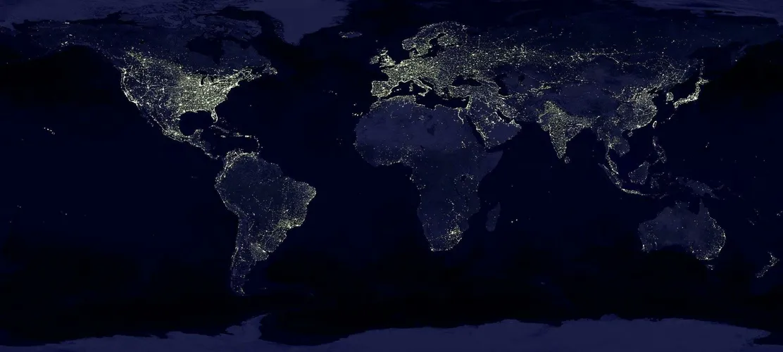 Satellite view of Earth at night with illuminated cities across continents.