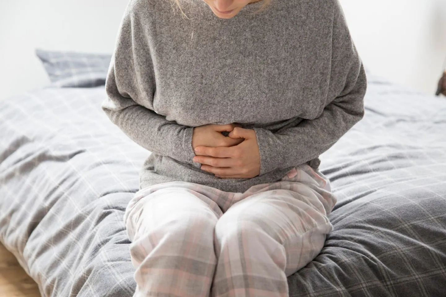 Sick woman with hands on stomach suffering from