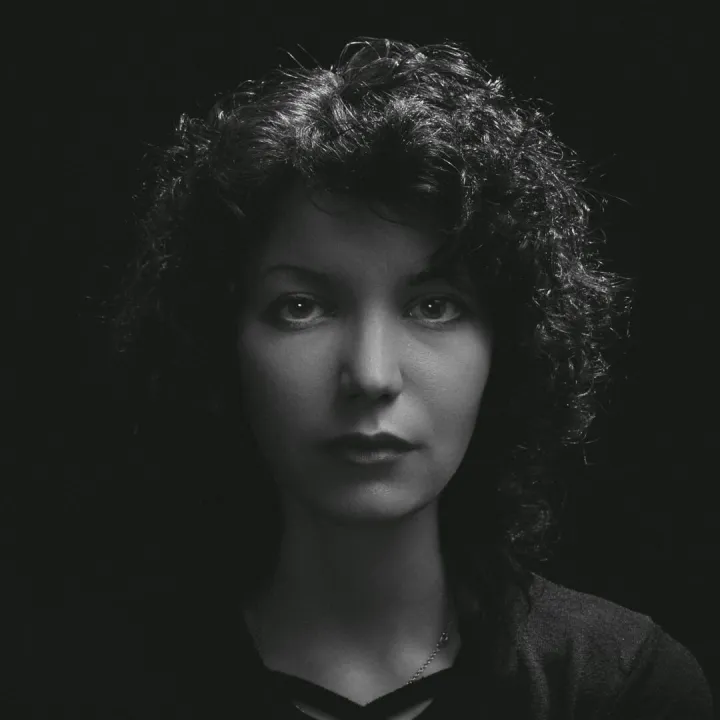 Black and white portrait of a woman with curly hair, highlighting moody and classic tones.