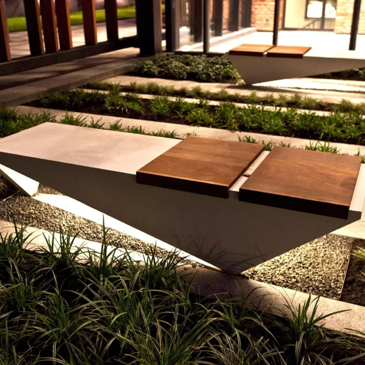 Modern concrete and timber bench set among ornamental grasses and gravel