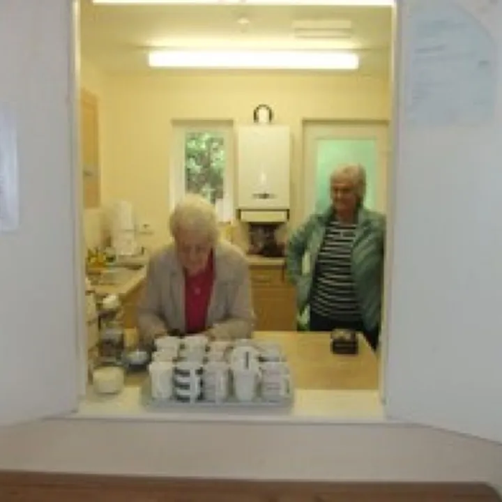 Volunteers serving refreshments through the hatch at Mawla Community Hall
