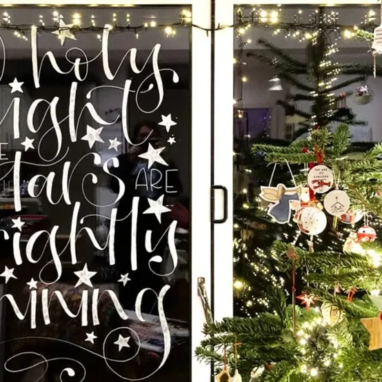 Hand painted Christmas window lettering reading Holy night all is bright