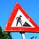 A red and white roadwork warning sign with a