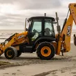 A JCB backhoe parked on the sandy shores of