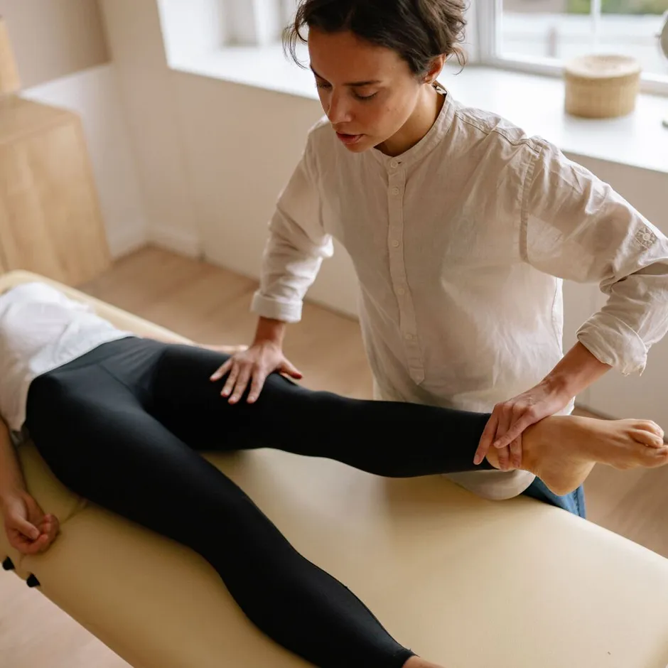 Physiotherapist guiding a client through a leg rehabilitation exercise