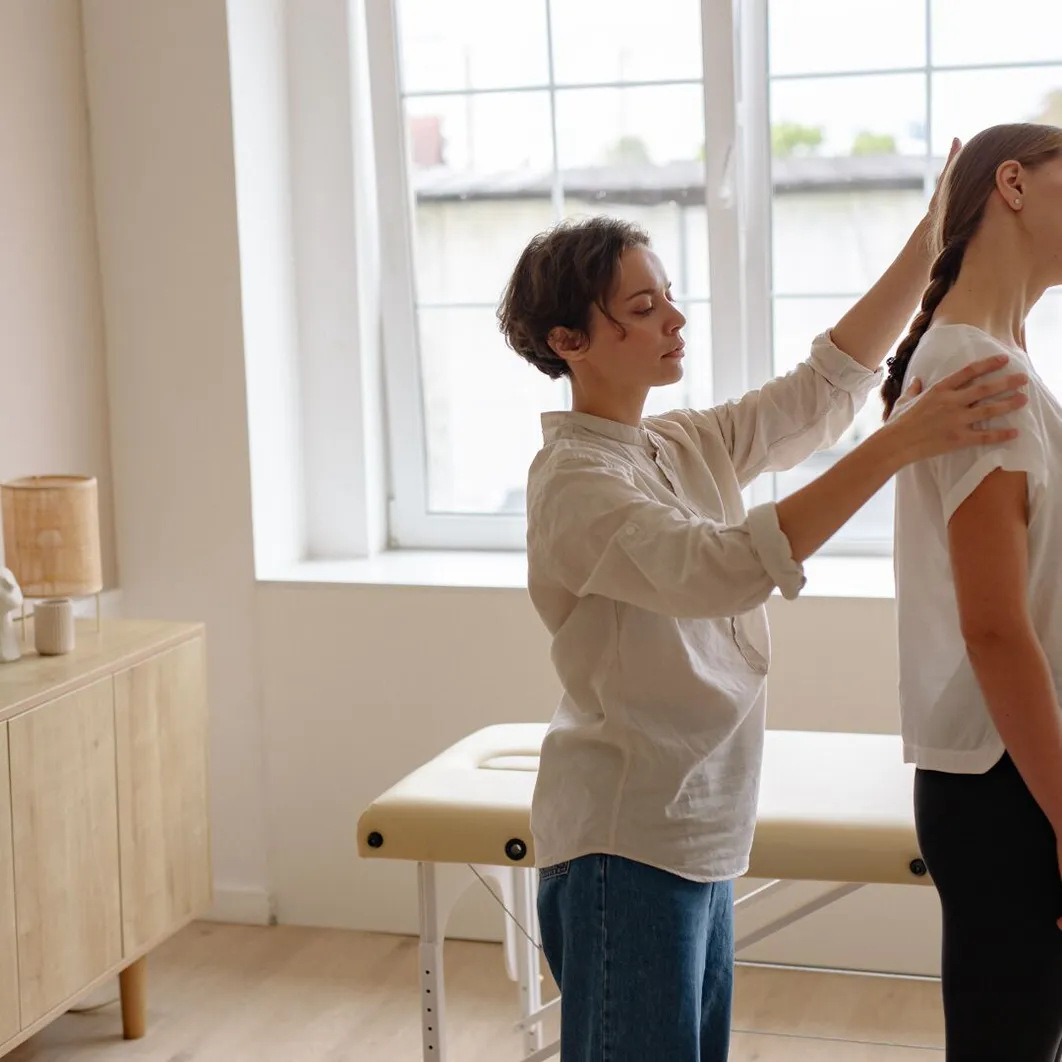 Physiotherapist assessing a client's posture by a window