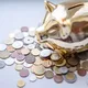 A golden piggy bank surrounded by assorted coins