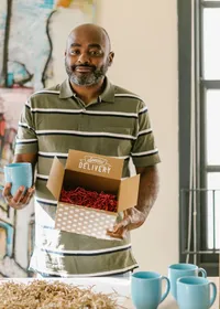 A small business owner packing coffee mugs into a delivery box