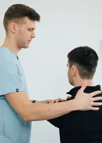 A physiotherapist assessing a patient’s shoulder in a clinic