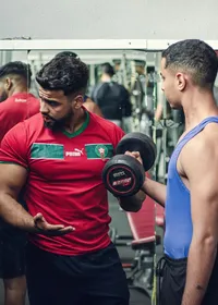 A personal trainer coaching a client lifting dumbbells in a gym