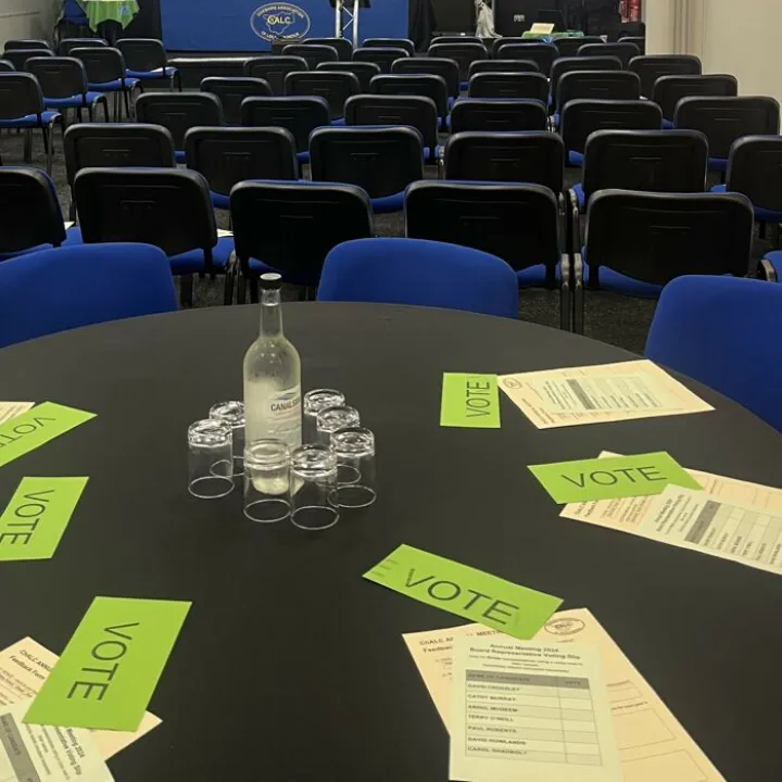 Meeting table set with water, glasses and green VOTE cards