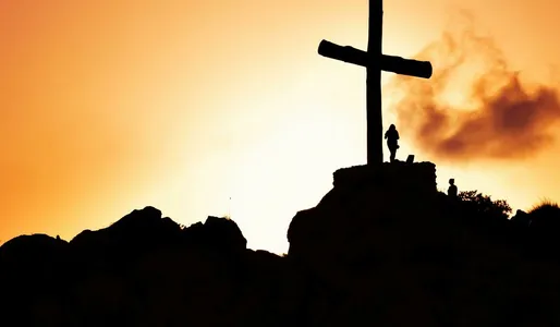 Majestic silhouette of a cross on a hill during a vivid sunset, symbolizing spirituality.