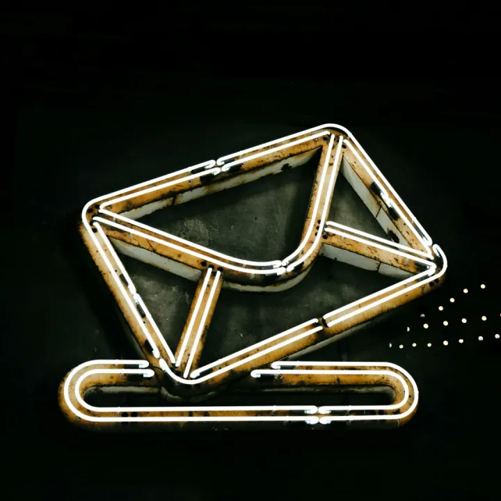 A glowing neon envelope symbol against a black background, conveying messaging or email concept.
