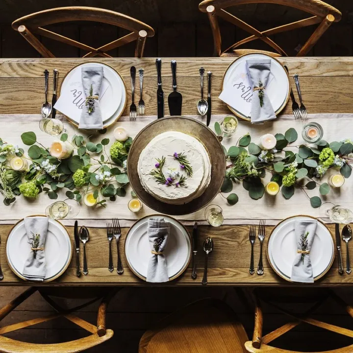 A long dining table laid for a private dinner, dressed with eucalyptus and white flowers