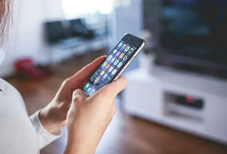 Woman browsing smartphone indoors, highlighting modern technology and communication in a cozy home setting.
