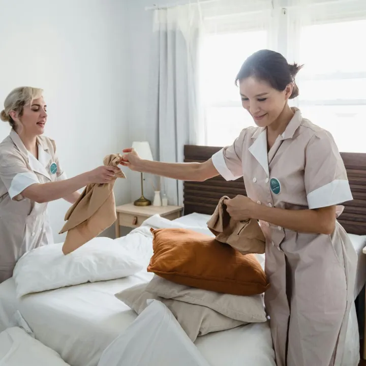 Two female housekeepers in uniform efficiently pre
