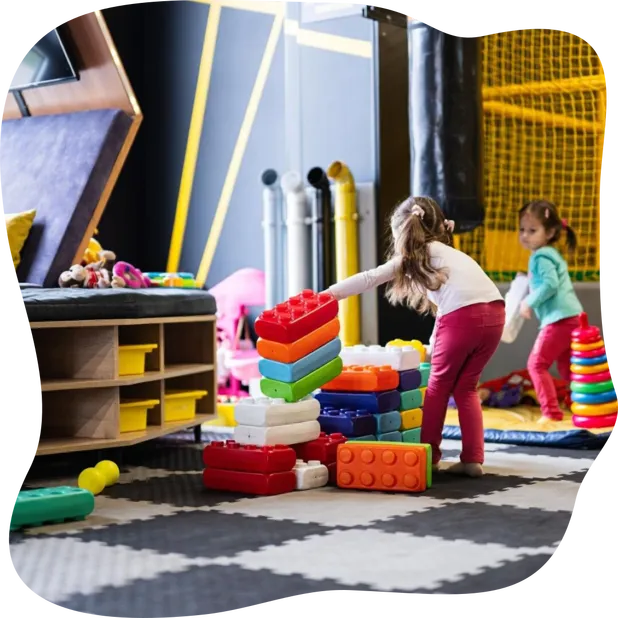 Two sisters playing at kids play center while build with col