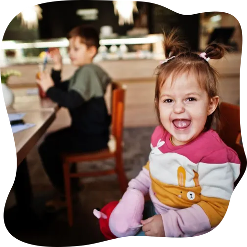Funny baby girl sitting in cafe and laughs