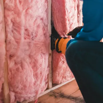 Focused worker installing pink fiberglass insulati