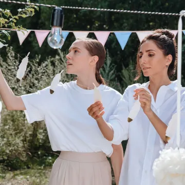 Two women decorating with feathers at an outdoor