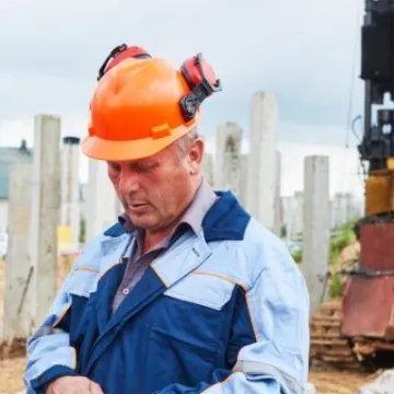 Construction workers  in front of pile driver machine
