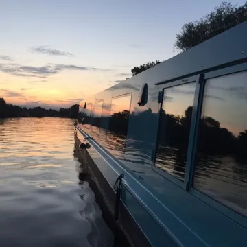 Eco boat sailing into the sunset on a canal waterway