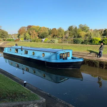 Blue solar-powered boat sailing on a canal waterway