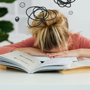 Young woman asleep over books at desk, conveying stress and mental overload.