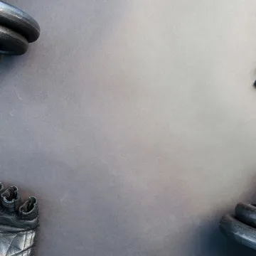 Flat lay of dumbbells and gloves on a workout surf