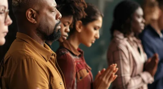 Diverse group of people praying together with closed eyes Sp